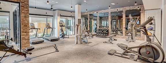 A spacious gym with a variety of equipment including treadmills, elliptical machines, and a rowing machine.