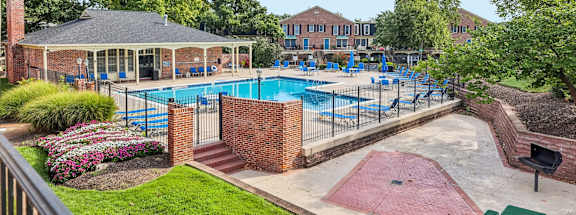 A pool area with a pavilion and a brick wall.