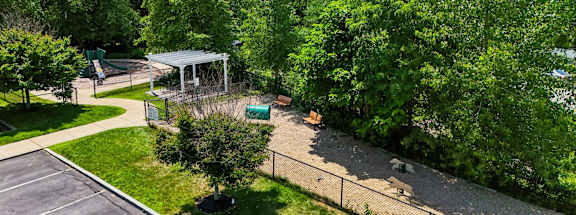 A parking lot with a fence and trees in the background.