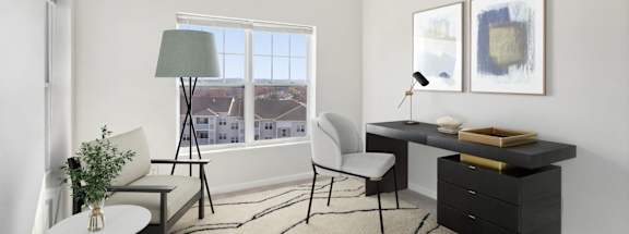 a living room with a desk and a window