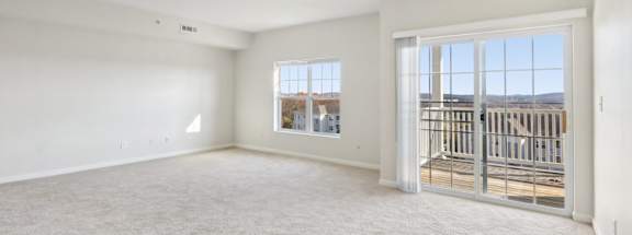 an empty living room with a sliding glass door to a balcony