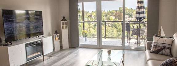 a living room with a couch and a television and a balcony
