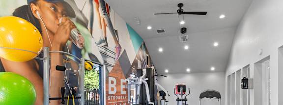 A gym with a variety of equipment including weights and exercise balls at Fusion Orlando Apartments.