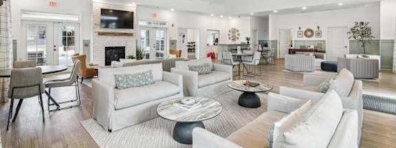 A spacious living room with white furniture and a fireplace.