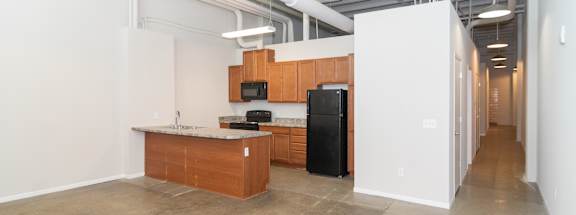 A kitchen area with a black fridge and microwave, a wooden counter, and a white wall.