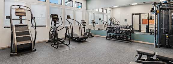 A spacious gym with a variety of equipment including treadmills, stationary bikes, and weight machines.