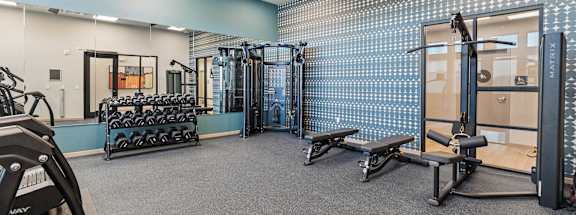 A gym with a variety of equipment including weights and benches.