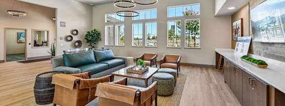 A well-lit waiting room with a green couch, brown chairs, and a wooden floor.