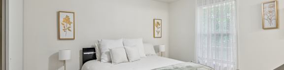 A bedroom with a bed, nightstand, and two pictures on the wall.