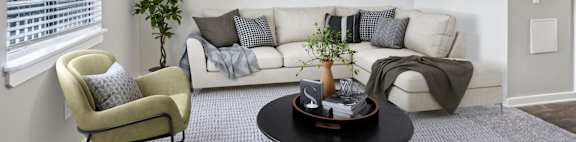 A living room with a white couch, a green armchair, a coffee table, and a ceiling fan.