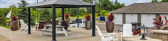 A gazebo is surrounded by patio furniture and potted plants.