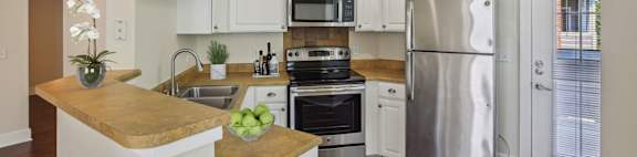 A modern kitchen with stainless steel appliances and wooden floors.