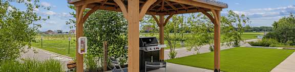 a pergola with a barbecue grill on a patio