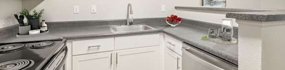 A kitchen with white cabinets and a stainless steel sink.