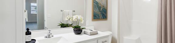 A white bathroom with a sink, toilet, and shower.