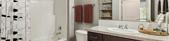 A bathroom with a white toilet, a white sink, and a shower curtain with black and white designs.