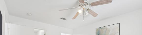 A bedroom with a large bed and a ceiling fan.