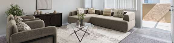 A living room with a grey sofa, a coffee table, and a large window.