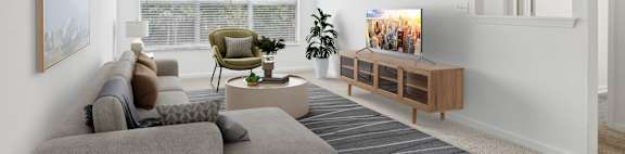 A living room with a grey sofa, a green armchair, a coffee table, and a television.