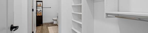 a white closet with shelves and a toilet in it