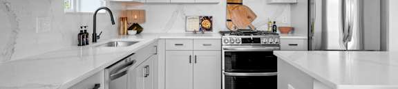 a white kitchen with stainless steel appliances and white counters