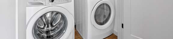 a white laundry room with a washing machine and a washer and dryer