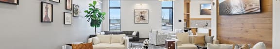 A living room with a white couch, a wooden table, and a large screen on the wall.