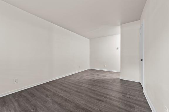 Empty room with wooden flooring and white walls.