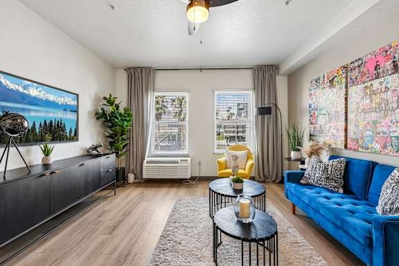A living room with a blue couch, a television, and a painting on the wall.
