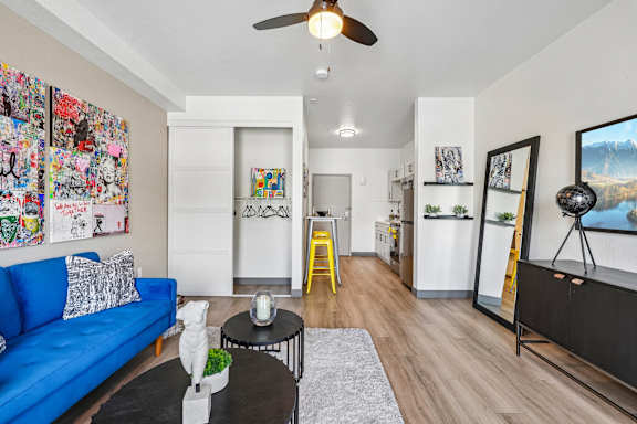 A living room with a blue couch, a coffee table, and a ceiling fan.