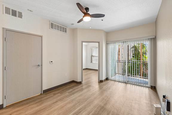 A room with a ceiling fan and sliding glass doors.