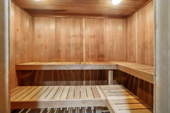 A wooden sauna with benches and a heater underneath.