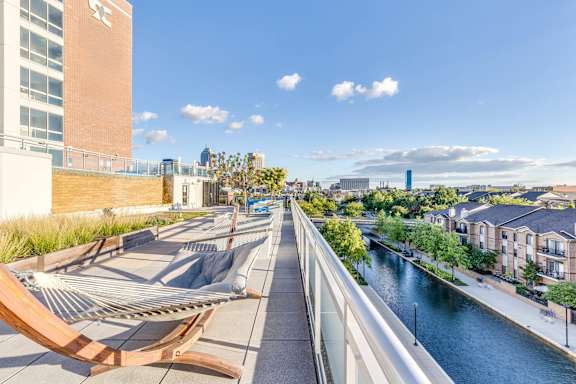 A hammock is strung between two buildings overlooking a river.