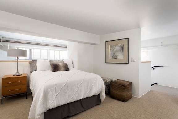 A bedroom with a large bed, a nightstand, and a picture on the wall.