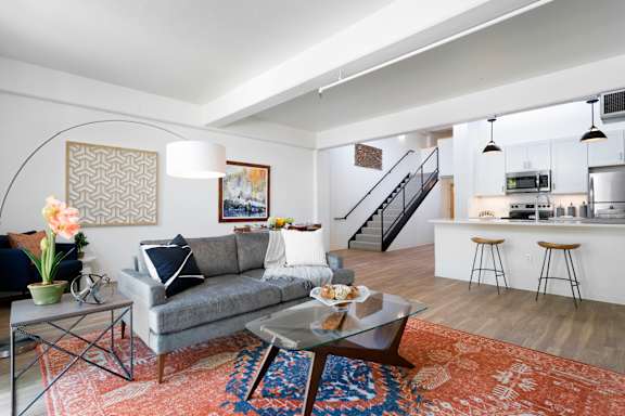 A living room with a grey couch and a glass coffee table.