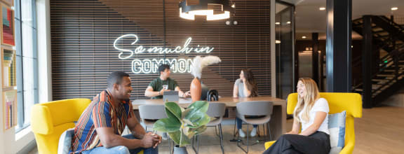 people sitting in yellow chairs in a room with a large sign on the wall