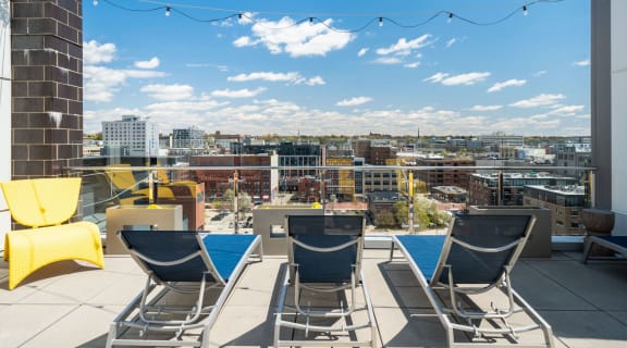 a rooftop deck with lounge chairs and a pool and a view of the city