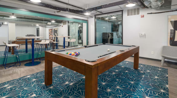 a pool table sits in the middle of a room with a bar in the background