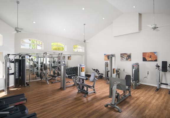 a spacious fitness room with hardwood flooring and white walls