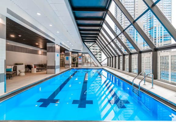a large indoor swimming pool with a glass walled ceiling and floor to ceiling windows