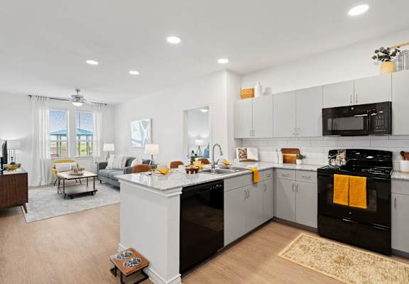 an open kitchen and living room with white cabinets and a counter top