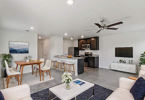 A modern living room with a dining area and kitchen in the background.