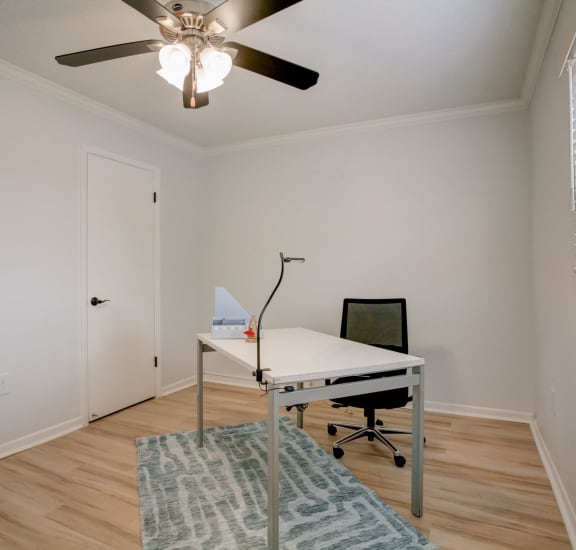 a home office with a white desk and a ceiling fan