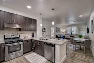 Modern open kitchen with stainless steel appliances, a marble countertop, and sleek cabinetry.