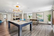 A pool table is in the middle of a room with wood flooring.