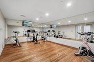A room with a wooden floor and a wall of exercise bikes.