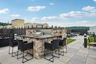 A stone bar with black chairs is set up on a patio.