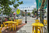 A yellow table and chairs are on the sidewalk outside a restaurant.