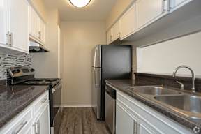 A kitchen with a black refrigerator and a stove top oven.