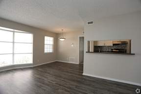 A spacious room with wooden floors and a large window.